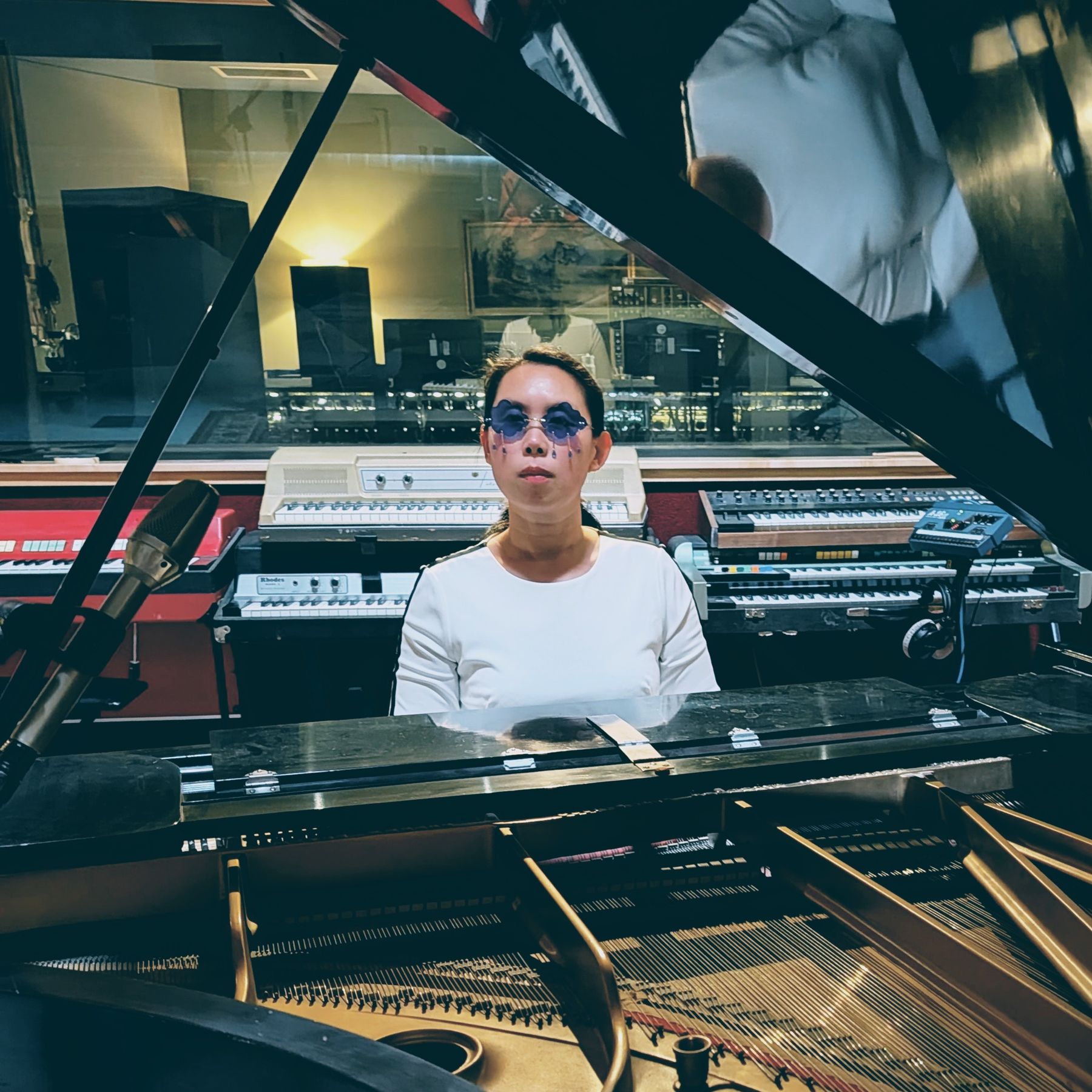 Michelle at the grand piano at Tiny Telephone, seen past the open lid, wearing violet teardrop sunglasses.